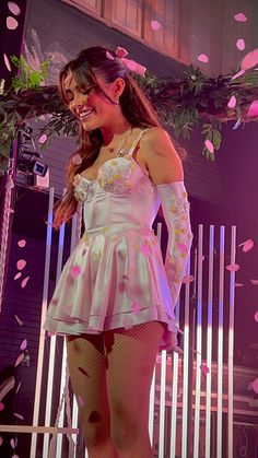 a woman standing on top of a stage wearing tights and heels with flowers in the air