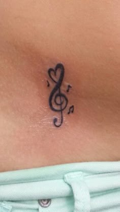 a woman's stomach with a musical note tattoo on the side of her chest