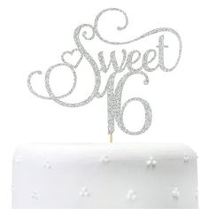 a white cake topped with a silver glitter sweet 16 topper and the words sweet sixteen written in cursive font