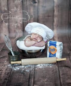 a baby is laying in a bowl next to some food and a whisk