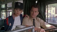 a man sitting next to a little boy on a bus wearing a baseball cap and tie