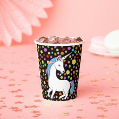 a paper cup filled with chocolate chips on top of a pink table next to stars