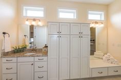 a large bathroom with white cabinets and marble counter tops, along with an open shower