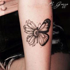 a black and white butterfly tattoo on the right arm, with a daisy in it's center