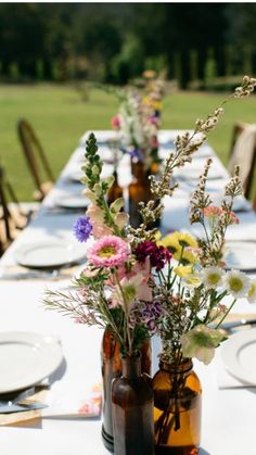 there are many bottles with flowers in them sitting on the table at this wedding reception