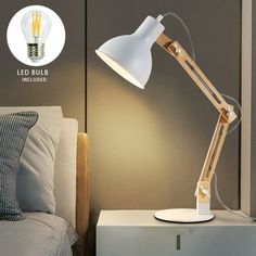 a lamp that is sitting on top of a nightstand next to a bed with pillows