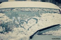 a car covered in snow with a heart drawn on the windshield and window sill