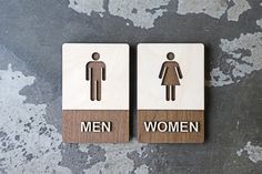 two wooden signs that say men and women on them, sitting on a gray surface