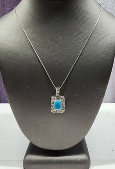 Own a piece of vintage beauty with this stunning pendant necklace. Crafted from 925 sterling silver, it features a rectangular cabochon-cut turquoise stone surrounded by marcasite accents in a bezel setting. Its 18-inch box chain with spring ring closure makes it the perfect accessory for any occasion, whether it be Mother's Day, Christmas, or just a day at the beach. The pendant has a timeless style and is signed by MO, making it an original piece from Thailand. This necklace is a must-have for any jewelry collection. Please review the pictures. They are a part of the description and ask any questions before purchase. Thank you! Elegant Turquoise Necklace With Rectangular Pendant, Elegant Turquoise Jewelry With Rectangular Stone, Elegant Turquoise Rectangular Stone Jewelry, Elegant Turquoise Necklace With Square Pendant, Elegant Turquoise Square Pendant Necklaces, Elegant Turquoise Square Pendant Necklace, Elegant Nickel-free Turquoise Necklace, Vintage Beauty, Box Chain