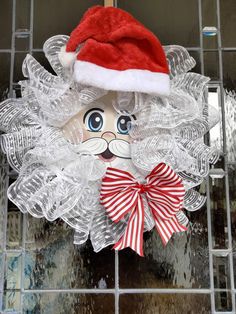 a christmas decoration with a santa claus hat on top of it's head and ribbon around its neck