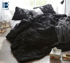 an unmade bed with black sheets and pillows on the floor next to a window