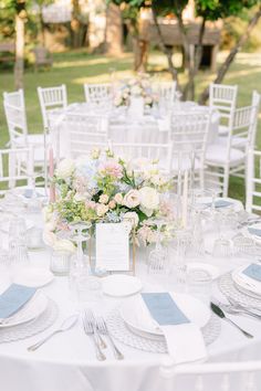 the table is set with white linens and silverware for an elegant wedding reception