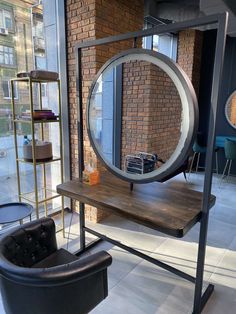 a desk with a mirror on it in front of a brick wall and chair next to it