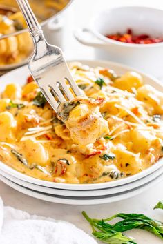 a fork is being lifted from a plate of ravioli with cheese and spinach