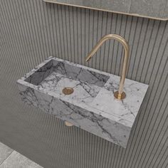 a marble sink with gold faucet handles on the wall next to a mirror