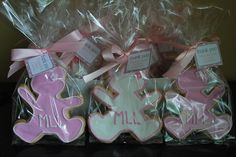 some decorated cookies in plastic bags with pink bows and ribbons on the top one is for a baby girl