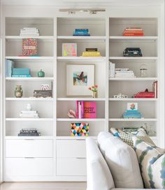 a living room filled with lots of white bookshelves