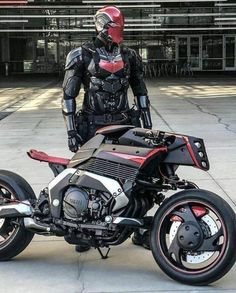 a man standing next to a motorcycle parked on top of a cement road in front of a building