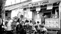 an old black and white photo of people sitting in front of a health clinic building