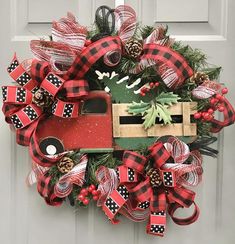 a christmas wreath with a red truck, pine cones and evergreens on the front door