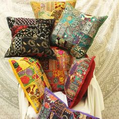 a pile of colorful pillows sitting on top of a white tablecloth covered floor next to a wall