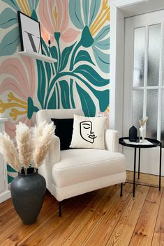 a living room with white furniture and colorful wallpaper