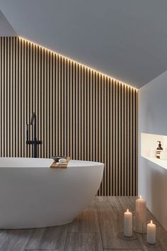 a white bath tub sitting in a bathroom next to a wall with candles on it