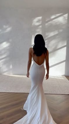 a woman in a white dress is standing on the floor with her back to the camera