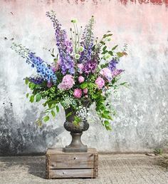 a vase filled with lots of purple and white flowers on top of a wooden crate