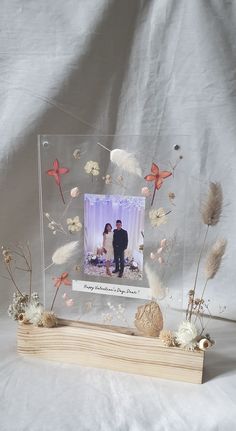 a photo frame with flowers and feathers in the shape of a couple on a wedding day