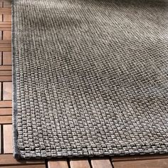 an outdoor area rug with wood flooring and tile on the ground, in front of a window