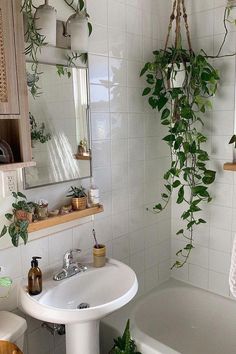 a bathroom with a sink, toilet and bathtub covered in greenery next to a mirror