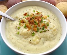 a white bowl filled with potato soup on top of a blue plate next to potatoes