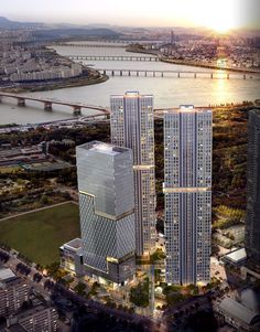 two tall buildings next to each other in front of a body of water and bridge