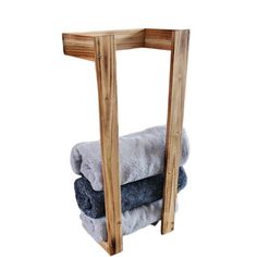 two towels are stacked on top of each other near a wooden rack with one towel hanging from it