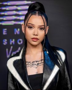 a woman with blue hair and piercings wearing a black leather jacket is looking at the camera