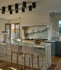 a large kitchen with marble counter tops and wooden chairs in front of an island that has two stools on it