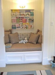 a room with a couch and some pillows on the floor next to a wall mounted book shelf