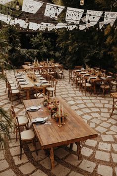 an outdoor dining area with wooden tables and white linens hanging from the ceiling, surrounded by greenery