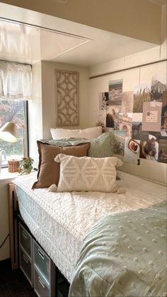 a bed with lots of pillows on top of it next to a window in a bedroom