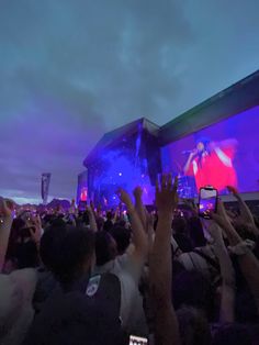 a large group of people at a concert with their cell phones up in the air