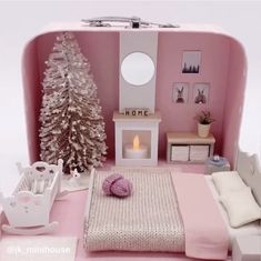 a dollhouse bedroom with pink walls and furniture, including a white christmas tree in the corner