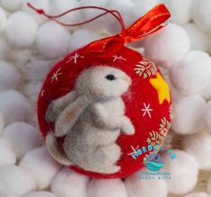 a red ornament with a white rabbit on it's side and some balls in the background