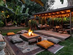 a fire pit in the middle of a yard with seating around it and lights on