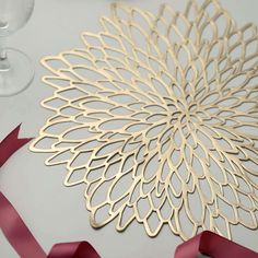 a table with some wine glasses and ribbon on top of it, next to a paper cutout that looks like a flower