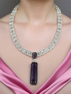 Lustrous Pink CZ stone with crystal-work combines with a delicate White gold frame to immediately effuse any ensemble with a dramatic dose of evening elegance! The set includes a pair of matching dangle earrings. Available in Pink and Amethyst Purple Dimension: 7" long, 2.25" pendant, 2.25" earrings Weight: 2.8 oz, w/ packaging 3.5 oz Luxury Amethyst Necklace With Diamond Accents, Luxury Purple Diamond Necklace, Fine Jewelry Diamond Necklace With Gemstone For Party, Luxury Purple Jewelry For Party, Purple Luxury Jewelry For Party, Purple Diamond Necklace With Gemstone Accents, Purple Diamond Necklace With Diamond Accents, Luxury Purple Jeweled Jewelry, Purple Diamond Pendant Necklace