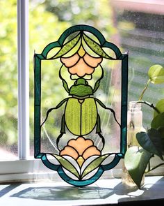 a stained glass window with a lady bug on it's side and green leaves in the background