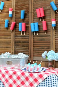 a table topped with blue and red marshmallows next to a wooden fence