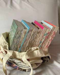 a bag filled with books sitting on top of a bed