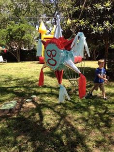 a young boy standing next to a kite shaped like a crab on top of grass